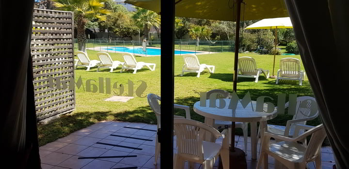 Terraza con mesa frente al jardín y la piscina